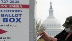 With the U.S. Capitol dome visible, a voter drops a ballot into an early voting drop box, Oct. 28, 2020, at Union Market in Washington.