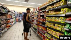 FILE: A customer compares prices while shopping at a Pick and Pay shop in East London, in the Eastern Cape province, South Africa, on March 17, 2023.