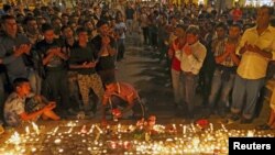 Migrants attend a candlelight ceremony at a railway station in memory of 71 refugees who died in a truck found in Austria, in Budapest, Hungary, Aug. 28, 2015.