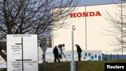 FILE - Members of media stand outside the Honda car plant in Swindon, Britain, Feb. 18, 2019.