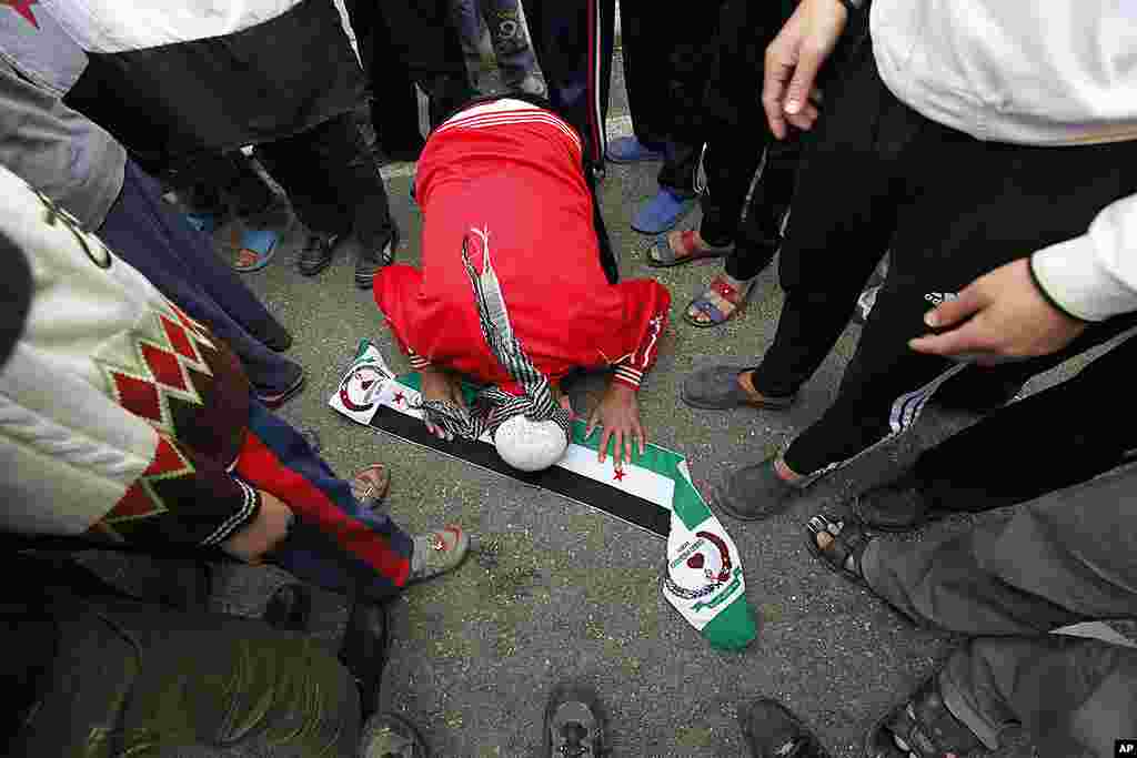 A Syrian refugees kisses a scarf with the colours of the Syrian Independence flag during a protest against Syria's President Bashar al-Assad at Boynuyogun refugee camp in Hatay province on the Turkish-Syrian border, March 16, 2012. (Reuters) 