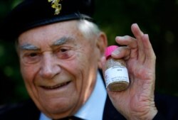 World War II veteran Bill Ridgewell, 94, holds a bottle filled with sand from Sword Beach, one of the D-Day beaches in Normandy, at his home in Shaftesbury, England, May 6, 2020.