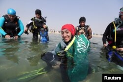 FILE - A female Saudi diver, wearing a Saudi national flag over her shoulders, smiles as she prepares to dive at a dive site in Dhahran, Saudi Arabia, Sept. 15, 2018.