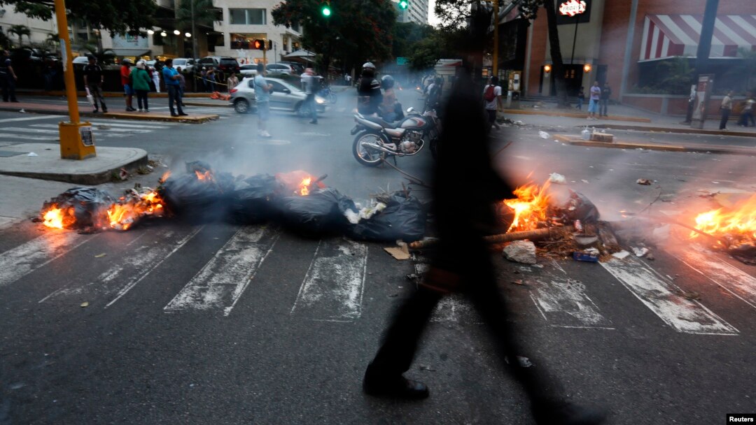 A man walks past a barricade set by anti-government protesters at Altamira square in Caracas, March 6, 2014.
