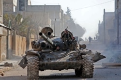 Turkey-backed Syrian fighters ride a tank in the town of Saraqeb in the eastern part of Idlib province in northwestern Syria, Feb. 27, 2020.