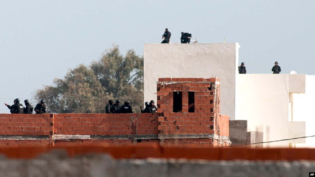 Tunisian anti-terrorist police forces (BAT) stand on roofs near a house where suspected Islamist militants were hidden in Raoued, near Tunis, Tuesday, Feb.4, 2014.