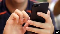 FILE - A person uses a smartphone in Chicago, Sept. 16, 2017. Many people reach out for help via texting because it is quiet and discreet.