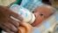 Cambodian orphan is fed formula milk by a nanny at Chrey Chao commune orphanage on the outskirts of Phnom Penh, May 12, 2004.