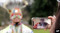 In this photo taken Saturday, April 4, 2020, moderator Whitney Rencountre, a Crow Creek Dakota tribal member, is seen on a screen from Rapid City, S.D., as he talks with Wakiyan Cuny, a Dakota and Lakota tribal member, during a live streamed powwow,…