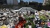 A car is seen amid a pile of garbage covered with white pesticide in the Palestinian refugee camp of Sabra in Beirut, Lebanon, July 23, 2015.