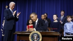 Presiden Obama menandatangani 23 perintah eksekutif untuk memerangi kekerasan senjata api, di Gedung Putih, Washington D.C., disaksikan oleh Wapres Joe Biden dan sebagian dari murid dan keluarga korban penembakan di SD Sandy Hook, Connecticut (16/1).