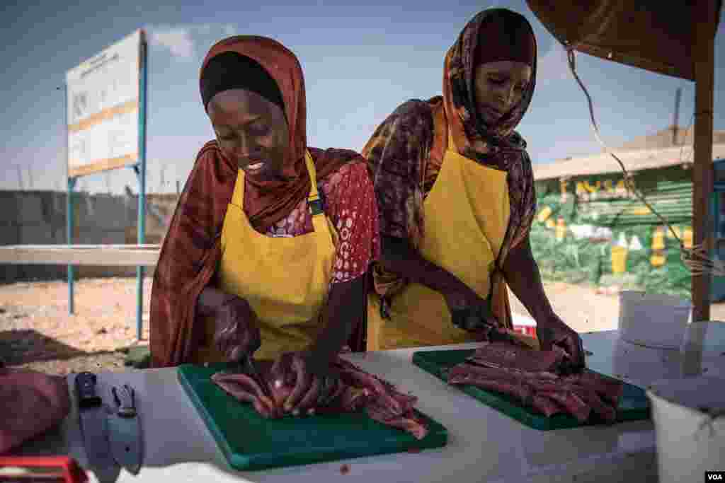 Women slice fresh fish in thin strips to dry for eventual sale as part of a Food and Agriculture Organization program to boost Somalia's fishing industry, in late March 2018. (J. Patinkin/VOA)