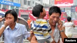 Un homme transporte un enfant secouru après un incendie dans l’immeuble d’une école maternelle à Ningde, dans la province de Fujian, Chine, 16 septembre 2015.