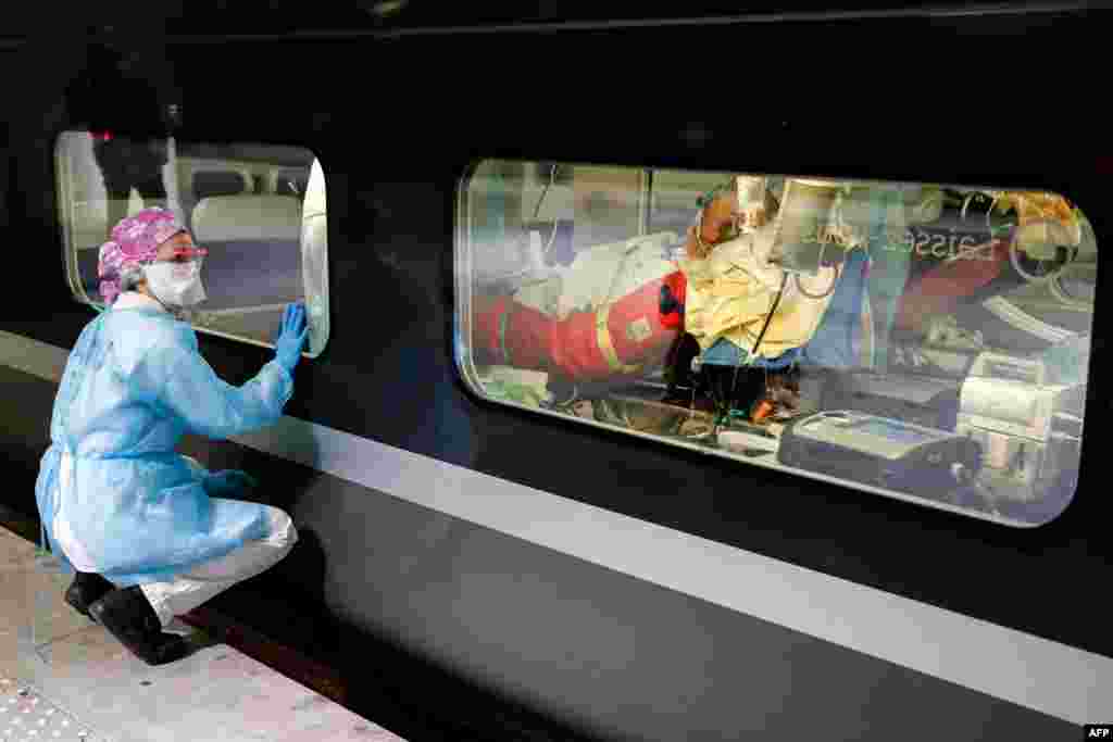 A medical staffer looks through the window of a medicalized TGV high-speed train at the Gare d&#39;Austerlitz train station in Paris, France, before its departure to evacuate patients infected with COVID-19 to other hospitals in the Brittany region.