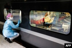 A medical staffer looks through the window of a medicalized TGV high-speed train at the Gare d'Austerlitz train station in Paris, France, before its departure to evacuate patients infected with COVID-19 to other hospitals in the Brittany region.