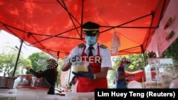 Mantan pilot Malaysia Azrin Mohamad Zawawi menyiapkan makanan di warung makannya di Subang Jaya, Malaysia, 7 November 2020. (Foto: REUTERS/Lim Huey Teng)