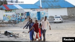 Pessoas carregam o cadáver de uma mulher não identificada, morta numa explosão que ocorreu quando pessoas nadavam na praia de Lido, em Mogadíscio