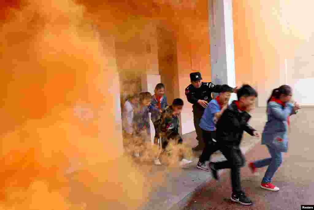 A police officer and schoolchildren take part in an anti-terrorism drill at a primary school in Huaibei, Anhui province, China, May 7, 2018.