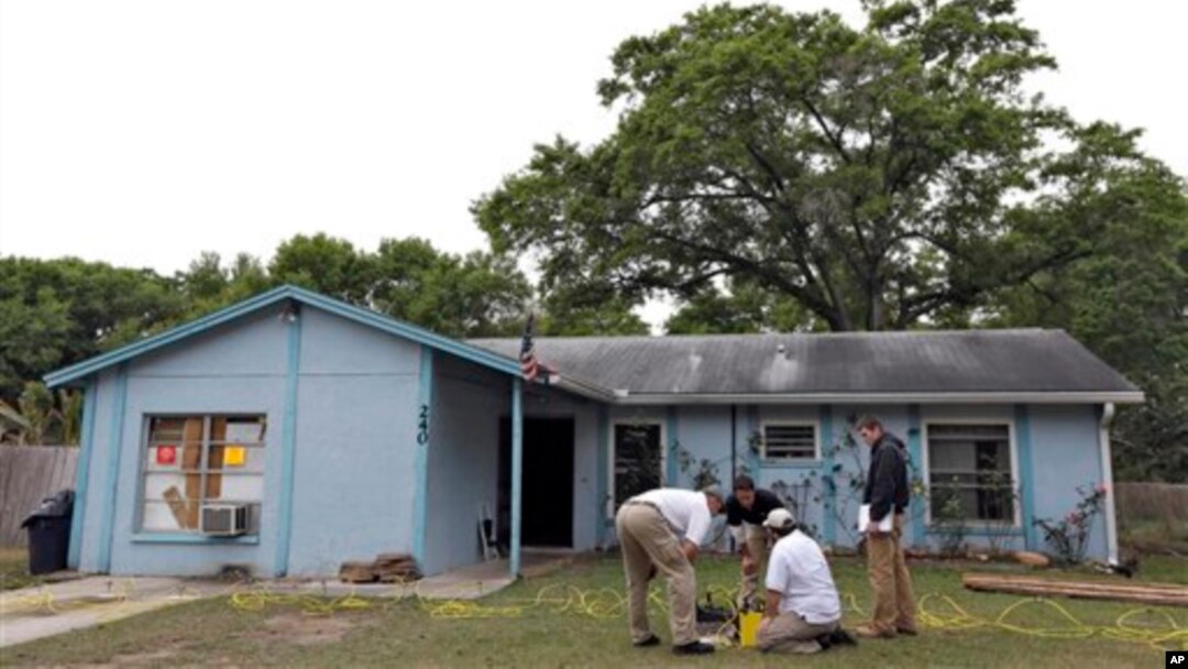 Engineers work in front of a home where sinkhole opened up underneath a bedroom and swallowed a man, in Seffner, Florida, March 1, 2013.