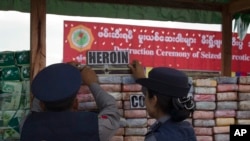 FILE - Myanmar police officers inspect seized drugs during a destruction ceremony of seized narcotic drugs on the outskirts of Yangon, Myanmar, Monday, June 26, 2017. 