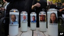 FILE - Photos of five journalists adorn candles during a vigil across the street from where they were slain in their newsroom in Annapolis, Md., June 29, 2018.