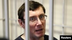 Ukraine's former interior minister Yuri Lutsenko looks out from defendant's cage during a court session in Kiev, Feb. 27, 2012