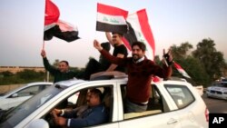 Warga Irak mengibarkan bendera nasional dalam perayaan kemenangan atas ISIS di Zona Hijau Baghdad, yang mulai dibuka Senin (10/12). 