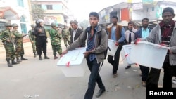 Anggota KPU memindahkan peralatan pemilihan untuk menghindari ancaman serangan di Bogra 5 Januari 2014. 