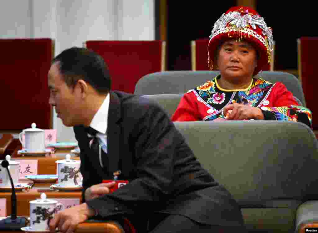 A delegate wearing a traditional costume sits down before the start of a meeting held on the sidelines of the 18th National Congress of the Communist Party of China at the Great Hall of the People in Beijing, November 8, 2012.