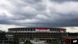 FILE - In this June 23, 2021, file photo, rain clouds move in over National Stadium, in Tokyo. Tens of thousands of visiting athletes, officials and media are descending on Japan for a Summer Olympics unlike any other. There will be no foreign fans,…