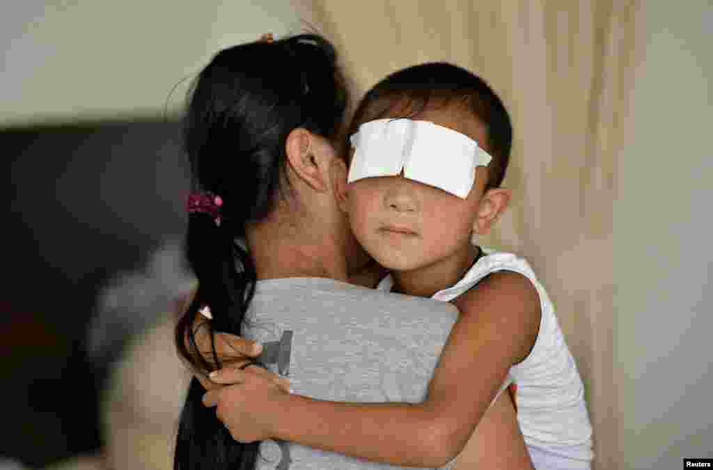 A six-year-old boy, whose eyes were gouged out, is held by his mother at a hospital in Taiyuan, Shanxi province. Chinese police suspect the boy&#39;s aunt of gouging out his eyes, Xinhua state news agency said, the latest twist in the investigation of a crime that shocked the country.