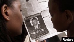 FILE - Women look at a newspaper June 12, 2002, in Nairobi, Kenya, featuring a photo of Rwandan businessman Felicien Kabuga, wanted in connection with Rwanda's 1994 genocide.