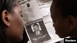 FILE - Women look at a newspaper June 12, 2002, in Nairobi, Kenya, featuring a photo of Rwandan businessman Felicien Kabuga, wanted in connection with Rwanda's 1994 genocide.
