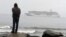 FILE - A man stands on the Bering Sea shore looking at the luxury cruise ship Crystal Serenity anchored just outside Nome, Alaska, Aug. 21, 2016. 