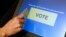 FILE - An elections official demonstrates a touch-screen voting machine at the Fairfax County Governmental Center in Fairfax, Virginia.