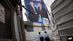 Two women walk through an alley past an election campaign billboard of the Likud party shows Israeli Prime Minister Benjamin Netanyahu, right, and US President Donald Trump in Bnei Brak, Israel, Sept 8, 2019. 