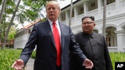 Presiden AS Donald Trump dan pemimpin Korea Utara Kim Jong Un dalam pertemuan pertama di Singapura, 12 Juni lalu, 