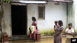 A family stands near their flooded home in Batticaloa district, about 320 km (199 miles) east of Colombo, February 6, 2011.