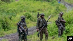 FILE - M23 rebels stand with theirs weapons during a ceremony to mark the withdrawal from their positions in the town of Kibumba, in the eastern of Democratic Republic of Congo, on Dec. 23, 2022