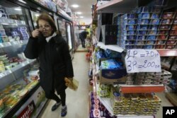 FILE - A woman shops in a grocery store, February 9, 2024 in Algiers. In Algeria, people have long relied on foreign currencies to buy imported items in short supply or finance their children's educations abroad.