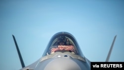 FILE - An F-35 pilot prepares for take off from the Vermont Air National Guard Base with the flag of the United States, before a flyover honoring Vermont’s front line coronavirus disease (COVID-19) responders and essential workers in Vermont, May 22, 2021