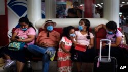 Tourists from Mexico wearing masks as a precaution against the spread of the new coronavirus, wait for their flight home, at the Jose Marti International Airport in Havana, Cuba, Monday, March 23, 2020.