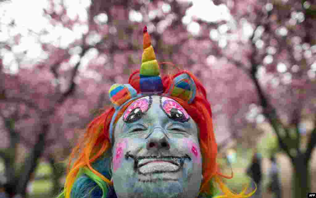 A man in a rainbow unicorn costume poses during the Cherry blossom Festival at the Botanic Garden in Brooklyn, New York, April 28, 2019.