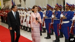 Cambodia's Prime Minister Hun Sen, left, reviews an honor guard with Myanmar's State Counselor Aung San Suu Kyi at the Peace Palace in Phnom Penh, Cambodia, Tuesday, April 30, 2019. (AP Photo Heng Sinith)