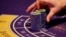FILE - a croupier counts the chips at a baccarat gaming table inside a casino during the opening day of Sheraton Macao Hotel at the Sands Cotai Central in Macau.