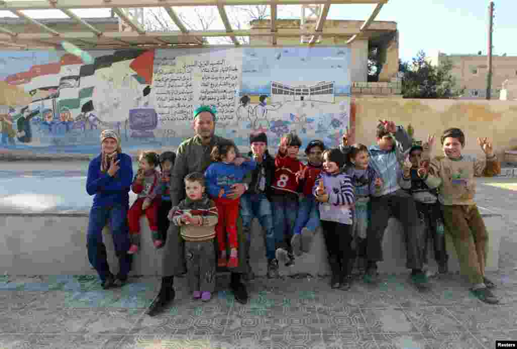 Internally displaced Syrian children sit on a bench at a school in Aleppo, January 14, 2013.