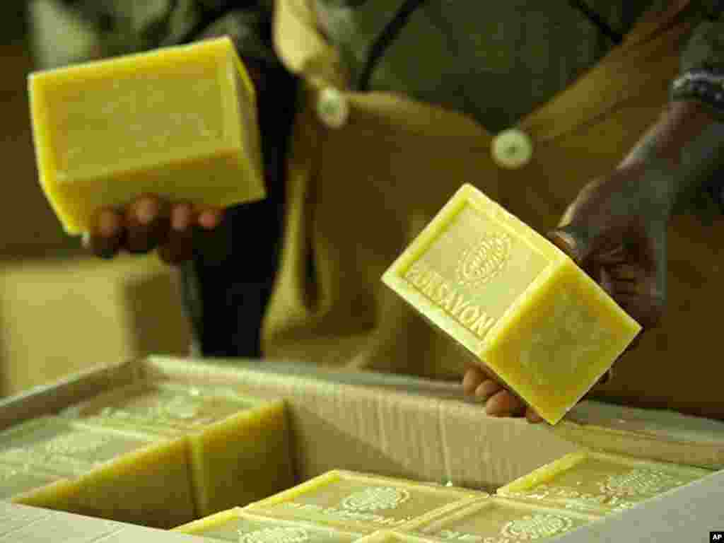 A worker showing a soap product manufactured by SIAT Gabon 