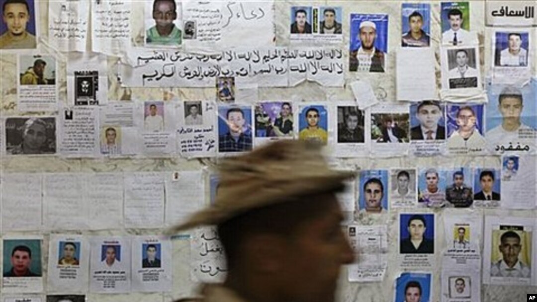 A soldier walks past a wall of posters appealing for information about missing people, at a hospital in Benghazi, Libya, April 17, 2011