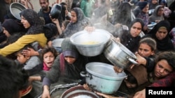 Palestinians gather to receive food cooked by a charity kitchen, before a ceasefire between Hamas and Israel takes effect, in Khan Younis, in the southern Gaza Strip, Jan. 17, 2025.