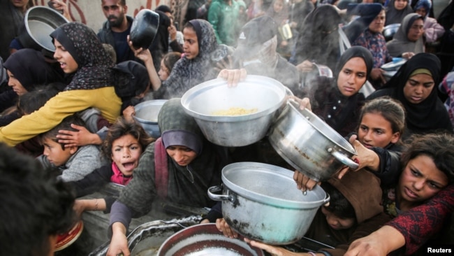 Palestinians gather to receive food cooked by a charity kitchen, before a ceasefire between Hamas and Israel takes effect, in Khan Younis, in the southern Gaza Strip, Jan. 17, 2025.